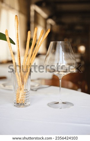 Italian food, grissini with a glass of white wine in a restaurant interior. Royalty-Free Stock Photo #2356424103