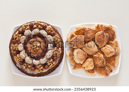 Fat lay of appetizing homemade pastries for family celebration. Festive cake decorated with nuts. Curd puff cookies in form of corners on white table
