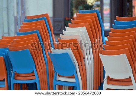 he plastic furniture of the outdoor cafe is stacked one on top of the other for the night