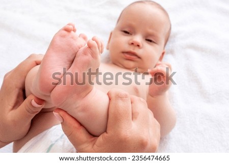 Mother's gentle touch on baby's legs. Concept of relieving infant constipation and colic Royalty-Free Stock Photo #2356474665