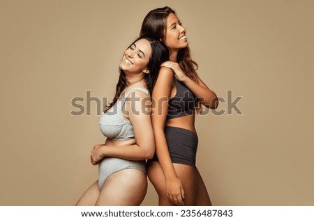 Laughing young arabic and middle eastern women in different underwear, enjoy free time, natural beauty care, isolated on beige background, studio. Fun, lifestyle, health care and fashion Royalty-Free Stock Photo #2356487843
