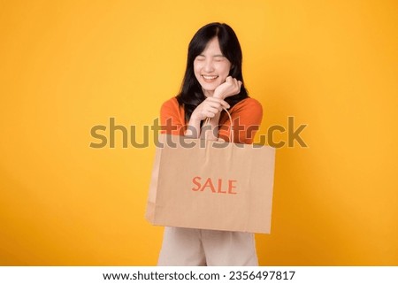 Elevate your shopping experience with love and the best deals. Smiling woman reveals purchases, capturing the thrill of discovering incredible savings. isolated on yellow background Royalty-Free Stock Photo #2356497817