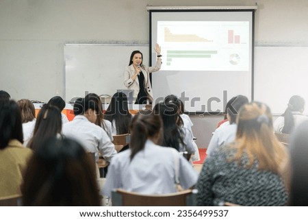 Education, teaching, learning concepts. Rear view of college students listening to teacher teach and explain lessons in classroom Royalty-Free Stock Photo #2356499537
