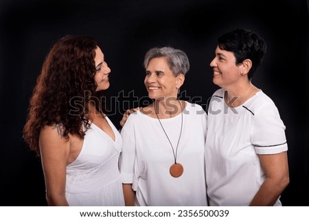 Three beautiful women, lesbians, musicians friends and happy posing for the camera. Studio portrait against black background.