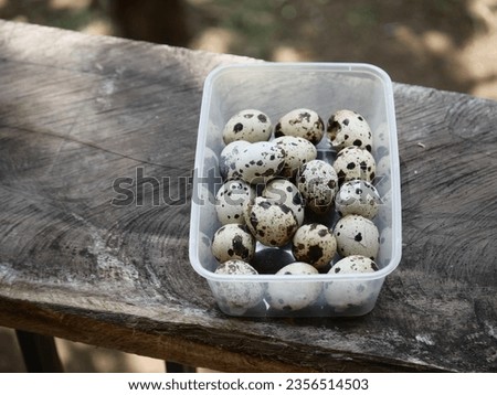 quail eggs in a plastic container on an old wooden background, taken with a top view.
