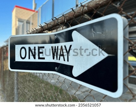 bent black and white one way sign pointing towards the viewer
