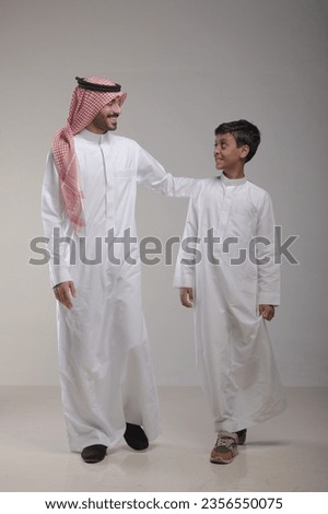 
A father with his son walking on a white background  Royalty-Free Stock Photo #2356550075