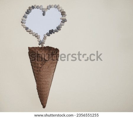 A waffle cone with a heart symbol made of stone on a yellow background. Flat lay. summer concept. Perfect for background.