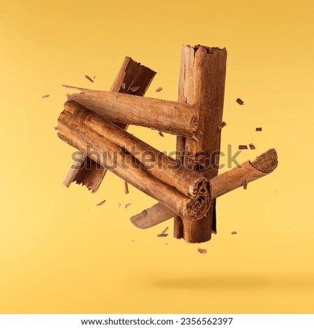 Fresh dried raw Cinnamon stick falling in the air isolated on yellow  backround. Food spices levitation or zero gravity conception. High resolution image. Royalty-Free Stock Photo #2356562397