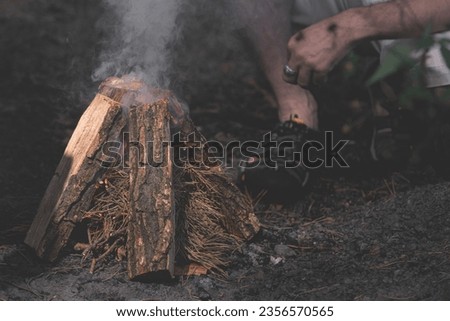A tourist makes a fire in the forest. A man makes a fire. Tourist skills. Rules of survival. Rest in nature. Go hiking. Wooden logs. Cook on an open fire.