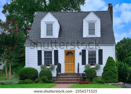 Small white clapboard house with dormer windows Royalty-Free Stock Photo #2356571525