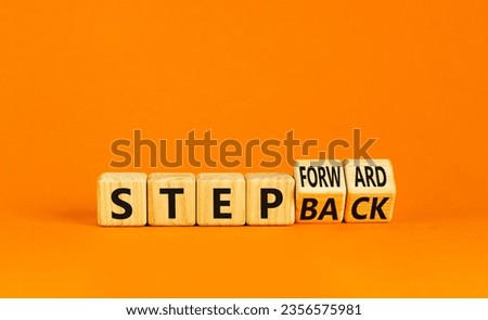 Step back or forward symbol. Concept words Step back Step Forward on wooden cubes. Beautiful orange table orange background. Businessman hand. Business step back or forward concept. Copy space.