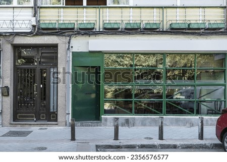 Frontal image of a commercial premises at street level with glass and iron enclosure painted green