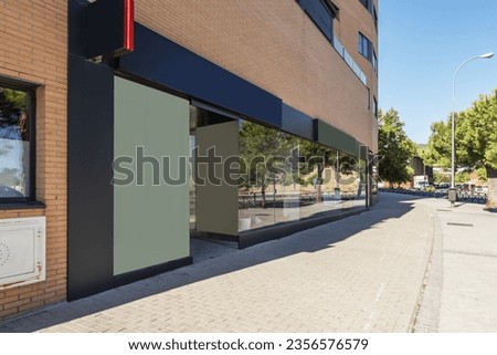 Image of a modern commercial premises at the foot of a wide street with plenty of trees with a large glass front on a very bright day