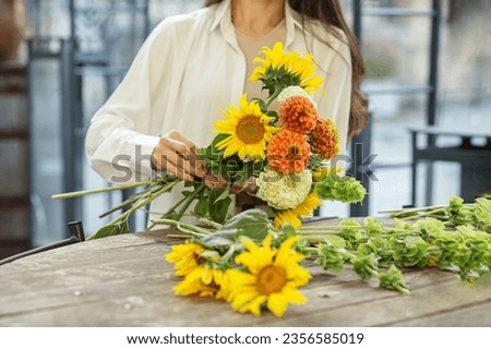 Startup successful small business entrepreneur owner woman standing with flowers and makes bouquet. Autumn.