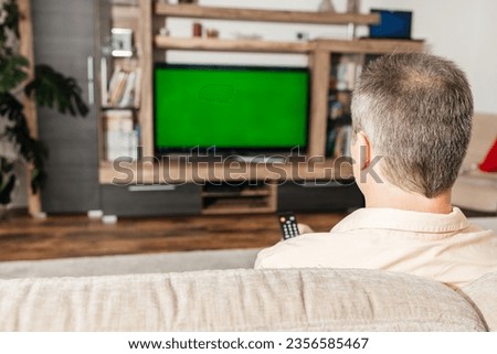 Man sitting on the sofa and watching TV in his free time