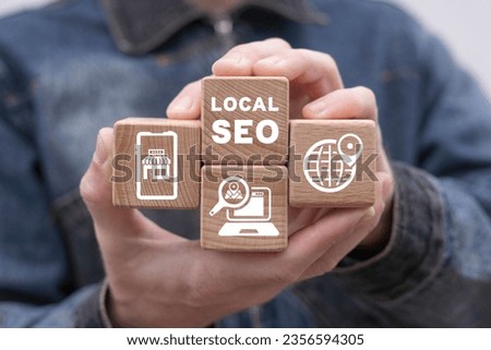Man holding wooden cubes with icons and inscription: LOCAL SEO. Local search marketing e-commerce. Concept of local seo strategy, local search optimization. Royalty-Free Stock Photo #2356594305