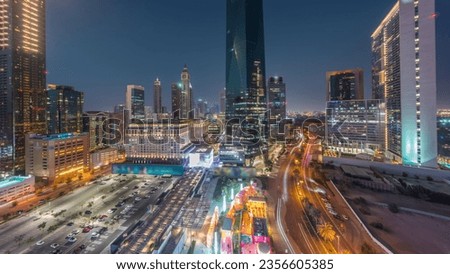 Dubai International Financial district day to night transition . Panoramic aerial view of parking lot and business office towers after sunset. Skyscrapers with hotels and shopping malls near downtown
