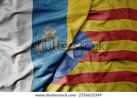 big waving national colorful flag of canary islands and national flag of catalonia . macro