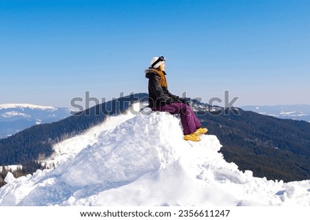 Women alpine girl in winter overalls sitting on snow hill looking at high Carpathian mountains at winter ski resort holiday, outdoor nature landscape, Ukraine, Europe.aerial view. Royalty-Free Stock Photo #2356611247