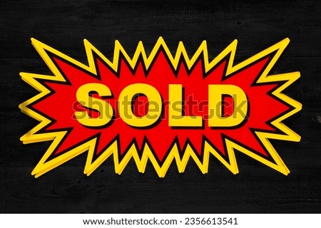 Red real estate sign with Sold in yellow on a black background. Real estate concept.