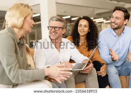 Group of smiling business people, colleagues talking, using laptop computer, planning startup, sharing ideas working together in modern office. Meeting, teamwork, successful business concept Royalty-Free Stock Photo #2356618915