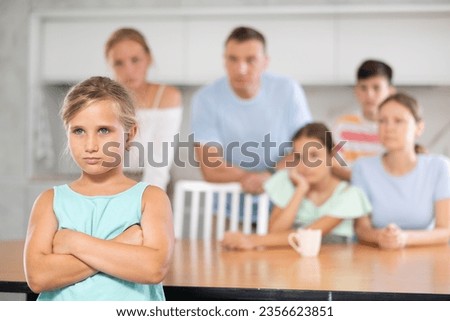 Sullen girl child crossed arms crossed over chest and is standing with back to parents and sisters with brother. Large family is outraged by negligent behavior of teenage daughter Royalty-Free Stock Photo #2356623851