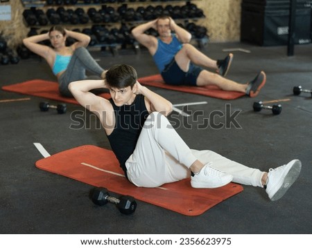 Concentrated sporty young guy doing ab exercises during intense bodyweight workout in gym.. Royalty-Free Stock Photo #2356623975