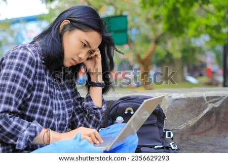 exhausted and stressed asian woman student working using laptop and study with text books in outdoors