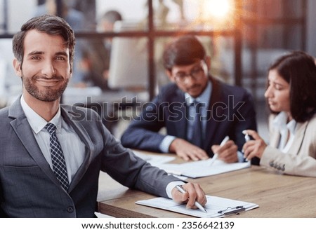 young man posing for the camera while sitting at the table in the office