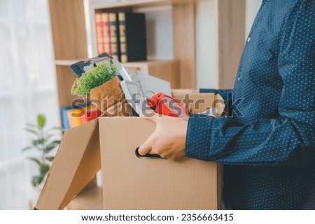Female firm employee leaving the office with cardboard boxes containing office supplies and personal items after quitting to find a new job, being fired, or being fired from the company. Royalty-Free Stock Photo #2356663415