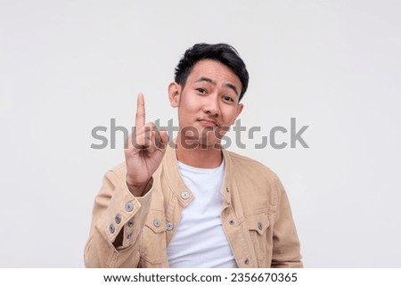 A smug handsome FIlipino guy in khaki jacket and white shirt pointing up, giving tips or insights. Isolated on a white background. Royalty-Free Stock Photo #2356670365