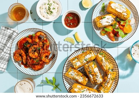 Grilled corn and tiger prawns with hot sauce and herbs. Summer dinner, Top view, Tile background.