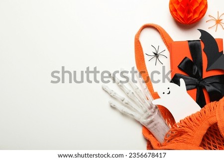 Gift box, paper ghost and bat in shopping bag on white background, space for text