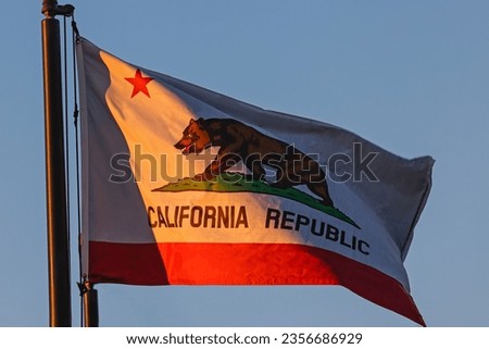 California state flag waving over the blue sky in a warm sunset light
