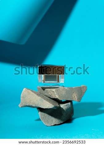 product jar standing on a stack of stones, light blue background, and shadow. product jar lying on stones. Mock-up plastic jar for skincare and lotion. copy space