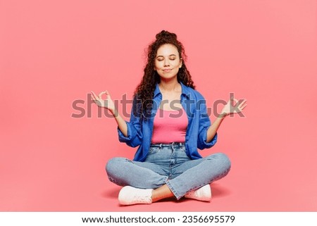 Full body young woman of African American ethnicity she wear blue shirt casual clothes hold spreading hands in yoga om aum gesture relax meditate try calm down isolated on plain pastel pink background Royalty-Free Stock Photo #2356695579