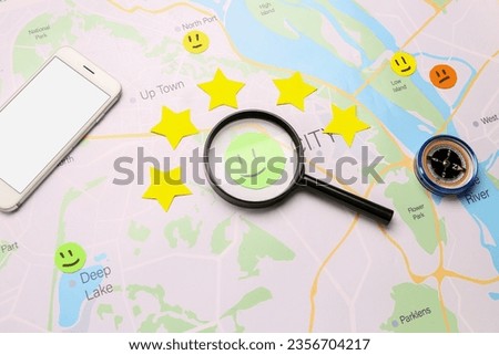 Magnifier with rating smiles, stars, compass and mobile phone on city map
