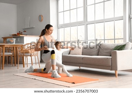 Sporty young woman with her little daughter training at home