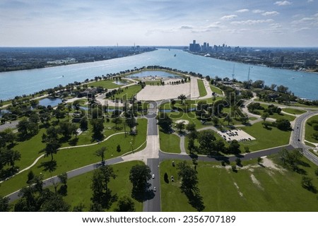 Aerial view of the Belle Isle island and the surrounding blue Detroit River with Detroit skyline in the background. Shot in Detroit, Michigan, United States.