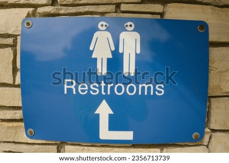 Googly eyes on a restroom sign, with the male and female icons appearing to look at each other.