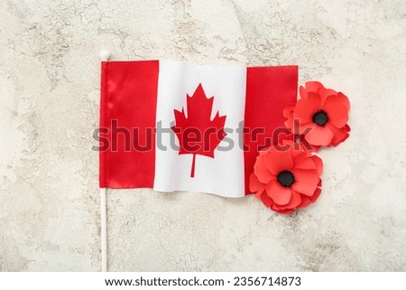 Poppy flowers with flag of Canada on light grunge background. Remembrance Day