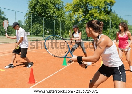 Energetic group participating in a high-energy cardio tennis training session, combining fitness and tennis skills Royalty-Free Stock Photo #2356719091