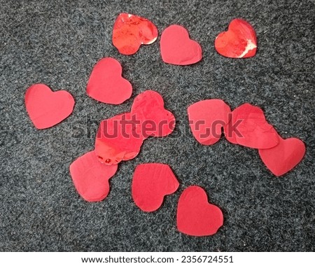 Heart-shaped pieces of paper scattered on the gray carpet