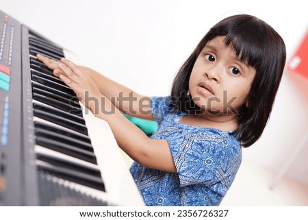 The cute little girl practiced electric piano at home