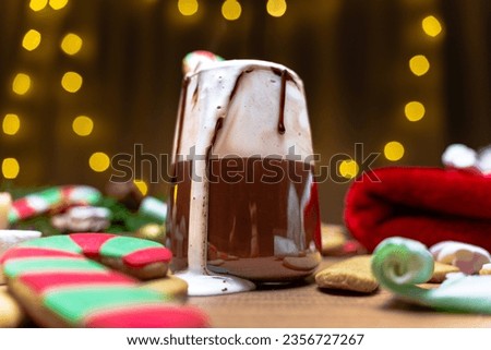 Christmas night, cream pouring from the glass of hot chocolate, close-up, with gingerbread cookies shaped like candy canes.
