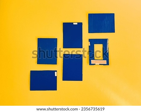 This picture presents an array of blue squares arranged on a vibrant yellow surface, forming a striking and contrasting composition.