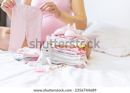 A pregnant woman is folding baby things. Selective focus. people.