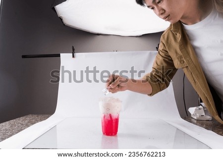 Asian Man taking picture of tasty drink in professional photo studio

