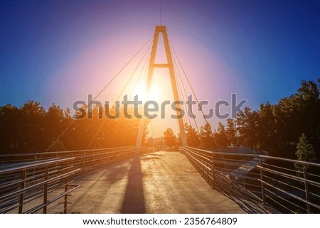 Modern footbridge with steel cables across the Anhor canal in Navruz park at sunset in summertime, Uzbekistan, Tashkent.